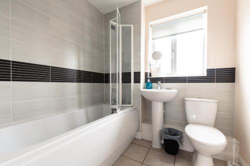 a bathroom with a toilet and a sink and a bath tub at Cheerful 4 Bedroom townhouse with free parking in Exhall