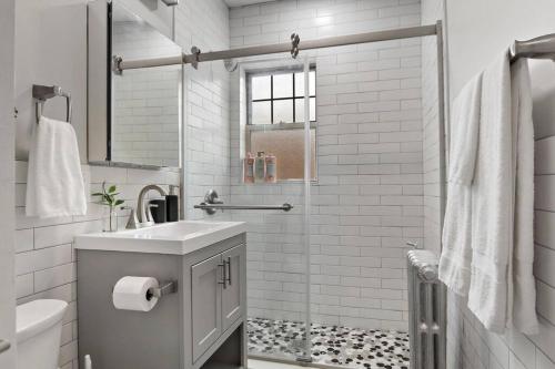 a white bathroom with a sink and a shower at Adorable 1BR Apt in Evanston with Onsite Laundry - Elmwood 105 in Evanston