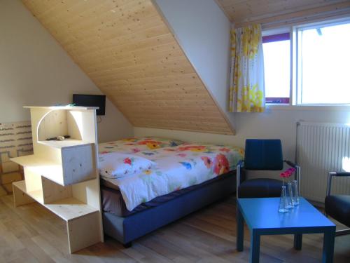 a bedroom with a bed and a chair and a table at B&B ZomersBuiten in Oude Pekela
