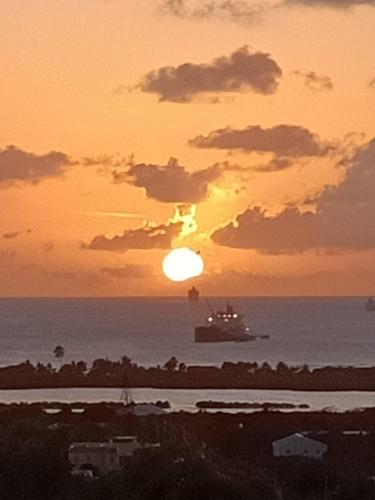 a boat in the ocean with the sunset in the background at Holiday Home Belvedere in Dickenson Bay