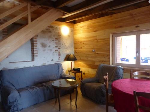 a living room with a blue couch and a table at Ferme éco-restaurée avec jardin, jeux enfants et parking près de Néris les Bains - FR-1-489-40 in Blomard