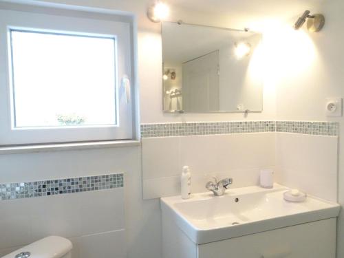 une salle de bain blanche avec un lavabo et un miroir dans l'établissement Terraced House in France near White Sand Beach, à Denneville