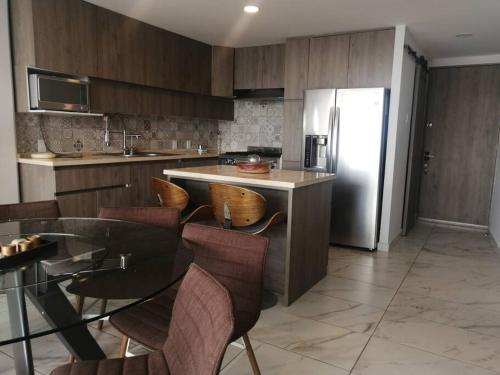 een keuken met een tafel en een roestvrijstalen koelkast bij Apartamento cerca de Centro CitiBanamex in Mexico-Stad