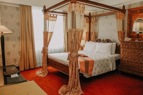 a bedroom with a four poster bed with curtains at Hotel Grand Q Gorontalo in Gorontalo