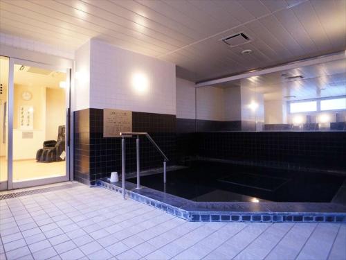 y baño con bañera y azulejos negros. en Green Rich Hotel Osaka Airport en Ikeda