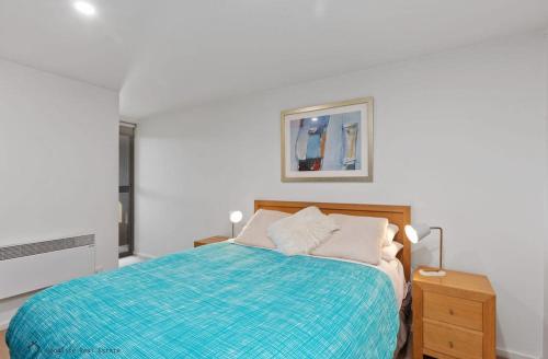 a white bedroom with a bed with a blue blanket at Apollo Blue Ocean View Unit 1-A Free WIFI in Apollo Bay
