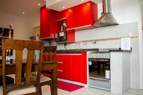 una cocina con armarios rojos y una mesa con comedor. en 9 ¾ Apartamentos VIP en La Falda