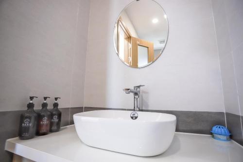 La salle de bains est pourvue d'un lavabo blanc et d'un miroir. dans l'établissement HAKU Boutique Hotel Quy Nhơn, à Quy Nhơn