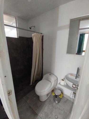 a white bathroom with a toilet and a sink at Estancia 311 Backpackers in Cajamarca