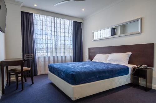 a bedroom with a bed and a desk and a window at Great Southern Hotel Perth in Perth