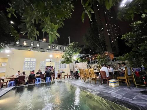 un grupo de personas sentadas alrededor de una piscina por la noche en Garden House Nha Trang en Nha Trang