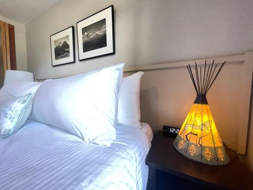 a bedroom with a bed with a lamp on a table at Windtower Lodge FullKitchen-Kingbed Suite-MntView-UGParking-Walk2DT in Canmore