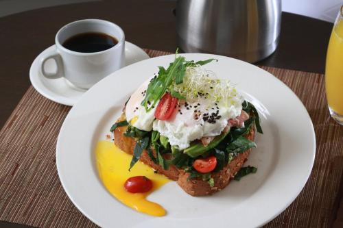 a white plate with a sandwich on a table with a cup of coffee at Holiday Inn Tuxpan - Convention Center by IHG in Tuxpan de Rodríguez Cano