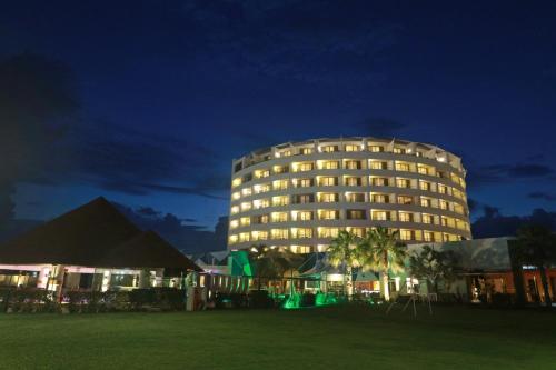 a building at night with a palm tree in front of it at Holiday Inn Tuxpan - Convention Center by IHG in Tuxpan de Rodríguez Cano