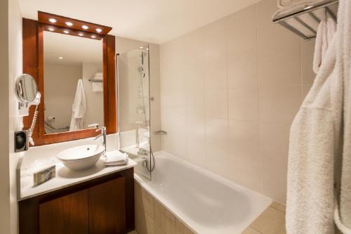 a bathroom with a tub and a sink and a mirror at Residhome Courbevoie La Défense in Courbevoie