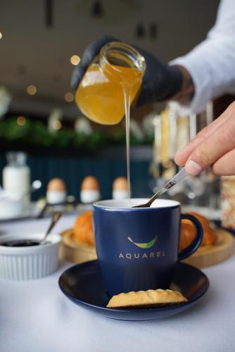 a person pouring coffee into a cup on a table at Hotel Boutique Aquarel in Zalău