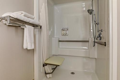 La salle de bains blanche est pourvue d'une douche et d'un tabouret. dans l'établissement Holiday Inn Express Campbellsville, an IHG Hotel, à Campbellsville