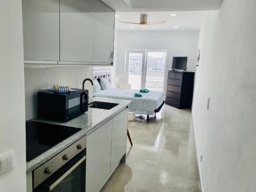 a kitchen with white cabinets and a room with a bed at Lagos Marina view apt on main avenue near beaches in Lagos