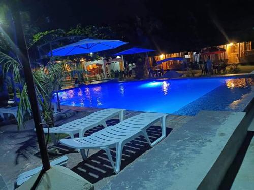 a pool with chairs and umbrellas at night at RRJ's BEACH RESORT in Oslob