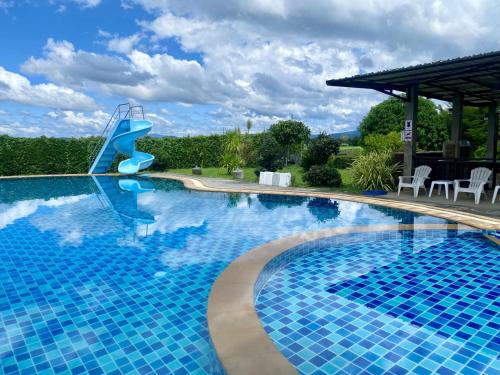 a blue swimming pool with a slide in a yard at Maerim Villa&Pool in Mae Rim