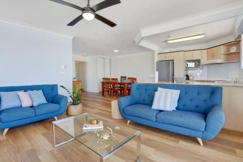 una sala de estar con 2 sofás azules y una mesa. en Beach Palms Holiday Apartments, en Gold Coast