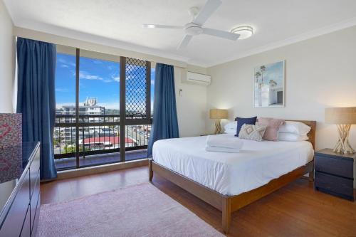 a bedroom with a bed and a large window at Beach Palms Holiday Apartments in Gold Coast