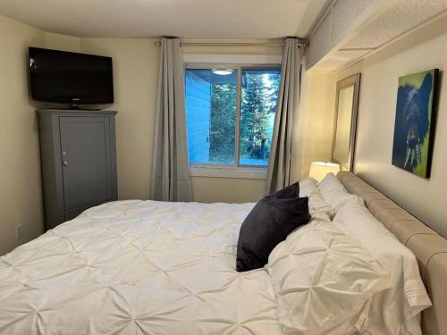 a bedroom with a white bed with a window at Bearcub Chalet in Big White