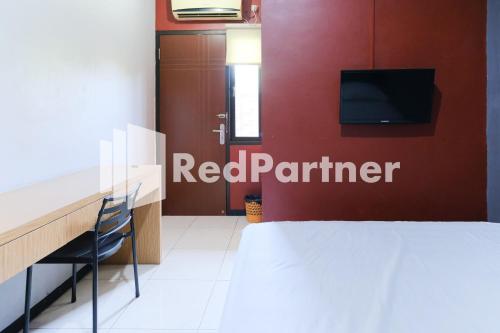 een slaapkamer met een bed en een tv aan de muur bij Dea Homestay Syariah Mitra RedDoorz At Kertomenanggal Surabaya in Siwalapkerto