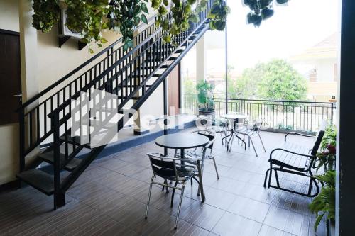 a balcony with tables and chairs and a staircase at Dea Homestay Syariah at Kertomenanggal Surabaya Mitra RedDoorz in Siwalapkerto