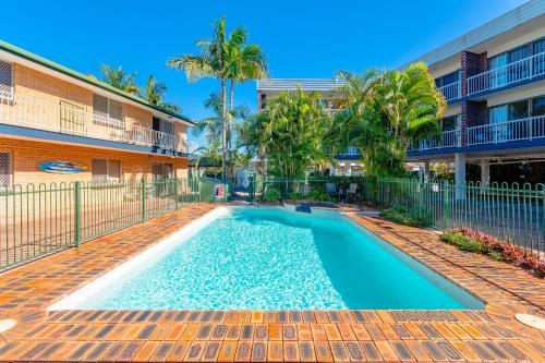 a swimming pool in front of a building with palm trees at Red Star Palm Beach in Gold Coast