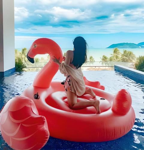 a girl sitting on an inflatable swan in a pool at Queen Ann Nha Trang Hotel in Nha Trang