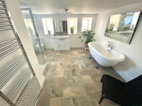 La grande salle de bains est pourvue d'une baignoire et d'un lavabo. dans l'établissement Oakhurst Boutique Apartment Llandudno, à Llandudno