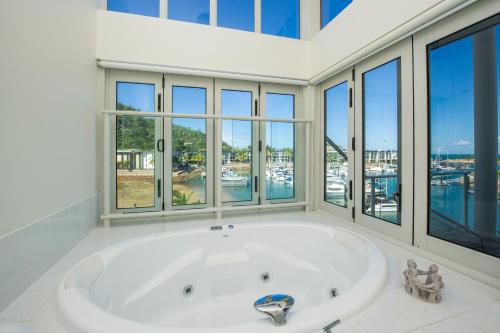 a large white bath tub in a room with windows at Beachside Magnetic Harbour Apartments in Nelly Bay