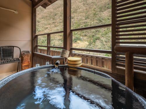 a bath tub in a room with a window at Hakkei in Maniwa