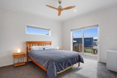 a bedroom with a bed and a ceiling fan at Sandy Retreat - Waihi Beach Holiday Home in Waihi Beach