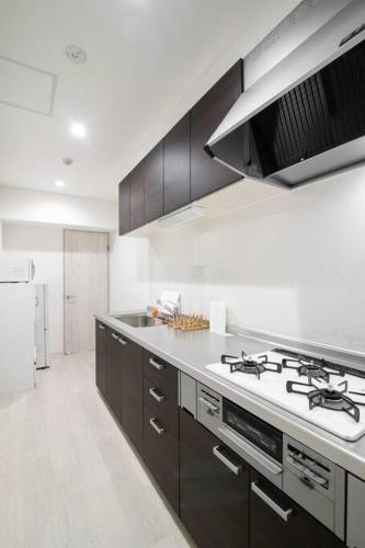 a white kitchen with a stove and a sink at HIRO BUILDING Apartment Stay in Fukuoka