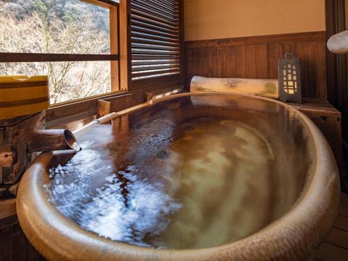 a large bath tub in a room with a window at Hakkei in Maniwa