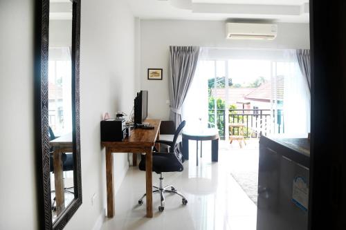 Zimmer mit einem Schreibtisch, einem Computer und einem Spiegel in der Unterkunft The Langstan Suites in Nai Harn Beach