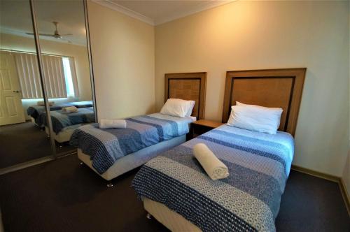 a hotel room with two beds and a mirror at Unit 27 Seafront Estate in Jurien Bay