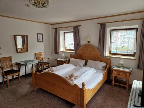 a bedroom with a large wooden bed and two windows at Gasthof Post in Mittersill