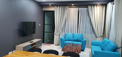 een woonkamer met blauwe stoelen, een tafel en een televisie bij Regalia Apartment B-3-1 Kota Samarahan in Kota Samarahan