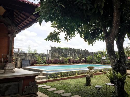 a swimming pool in a yard with a tree at Escotel Villa Marga in Tabanan