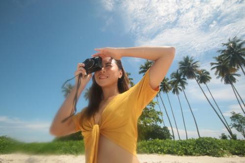 a woman taking a picture on the beach with a camera at Arasatu Villas & Sanctuary in Maratua Atoll