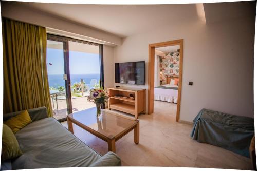 a living room with a couch and a table and a television at Serenity Amadores in Puerto Rico de Gran Canaria