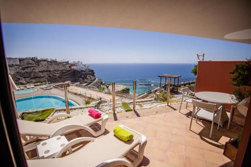 a balcony with a view of a pool and the ocean at Serenity Amadores in Puerto Rico de Gran Canaria