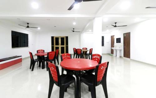 a dining room with red chairs and a red table at STAYMAKER Gharana Resort in Bolpur