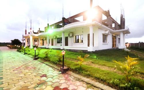 a white house with lights on the side of it at STAYMAKER Gharana Resort in Bolpur