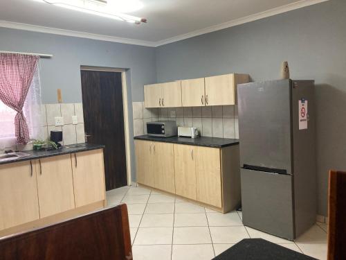 a kitchen with wooden cabinets and a stainless steel refrigerator at Daffodil self catering and accommodation A in Swakopmund