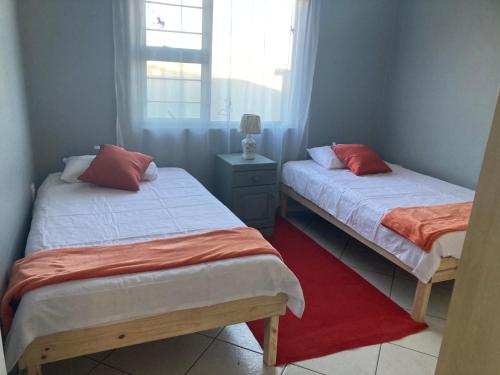 two beds in a small room with a window at Daffodil self catering and accommodation A in Swakopmund