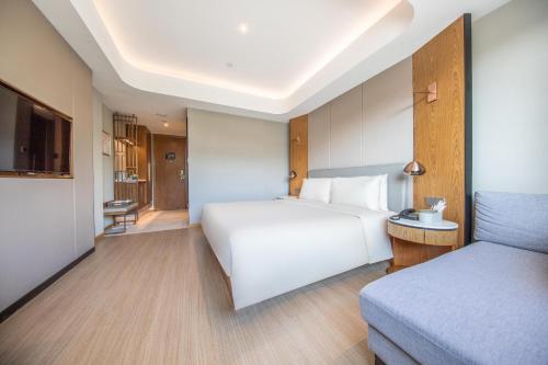 a hotel room with a white bed and a couch at Atour X Hotel Yantai Penglai Pavilion in Penglai